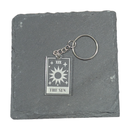 The Sun Tarot Card Keychain engraved on clear acrylic and displayed on a slate tile for contrast