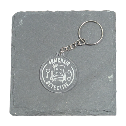 Armchair Detective image engraved on acrylic keychain displayed on slate tile for contrast