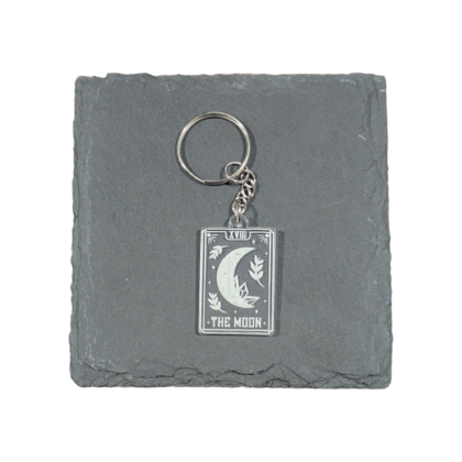 The Moon Tarot Card Keychain engraved on clear acrylic and displayed on a slate tile for contrast