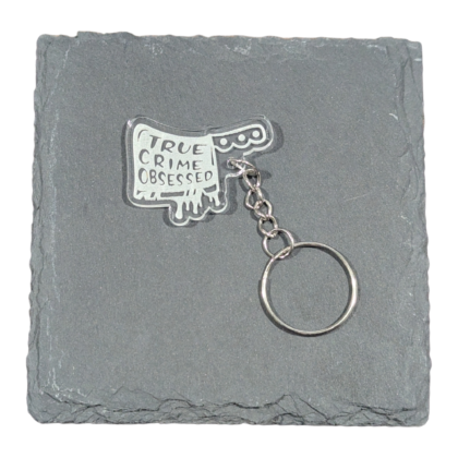 True Crime Obsessed words on Cleaver image engraved on acrylic keychain displayed on slate tile for contrast